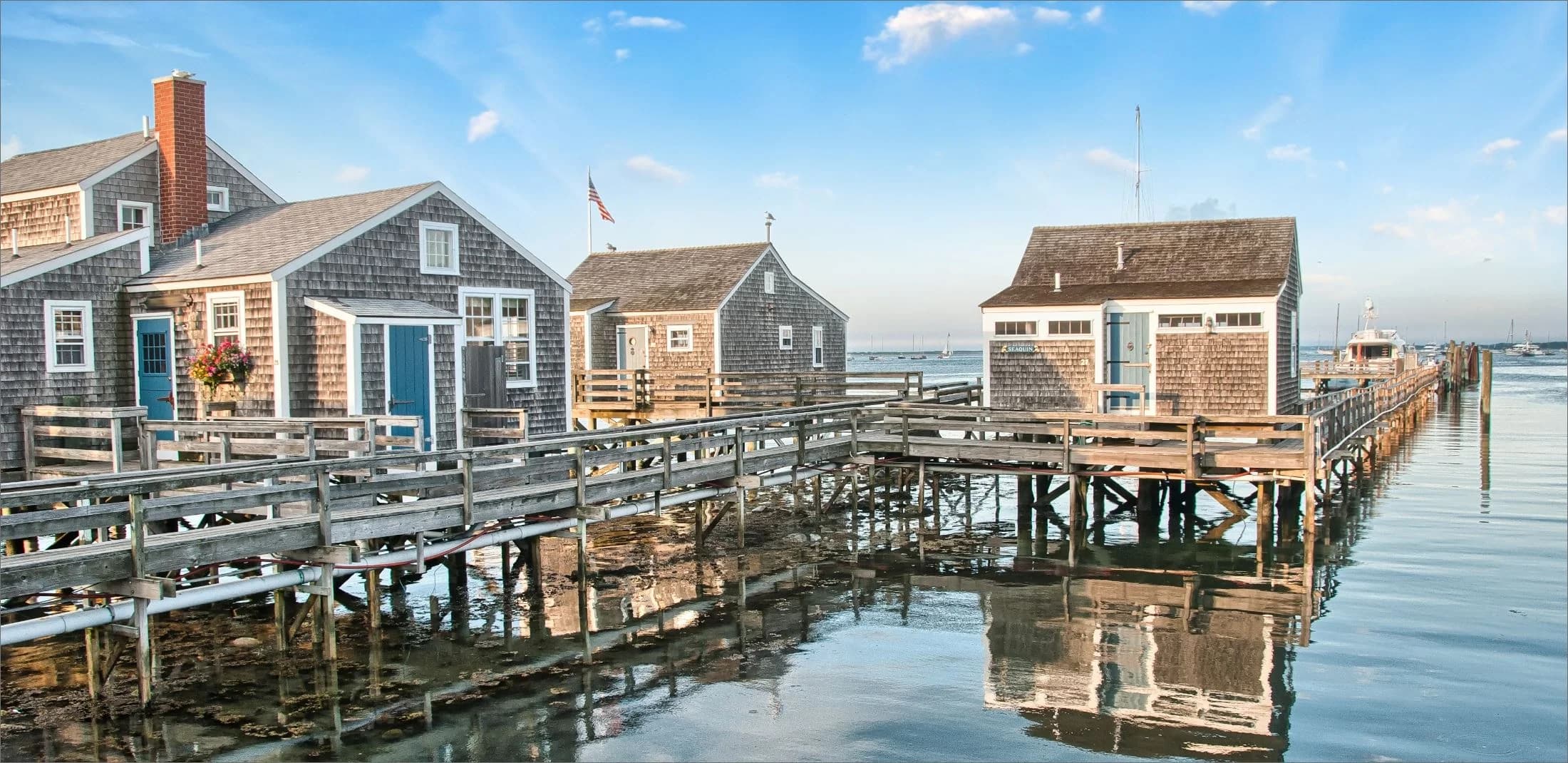 Historic grey-shingled wharf buildings on stilts over Nantucket harbor