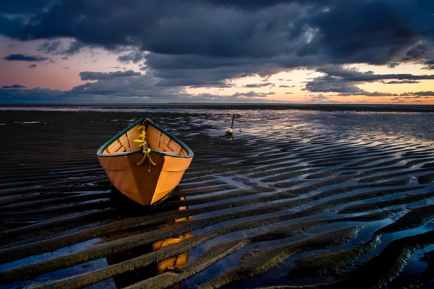 A wooden dinghy resting on the sand beside the Cape Cod shoreline