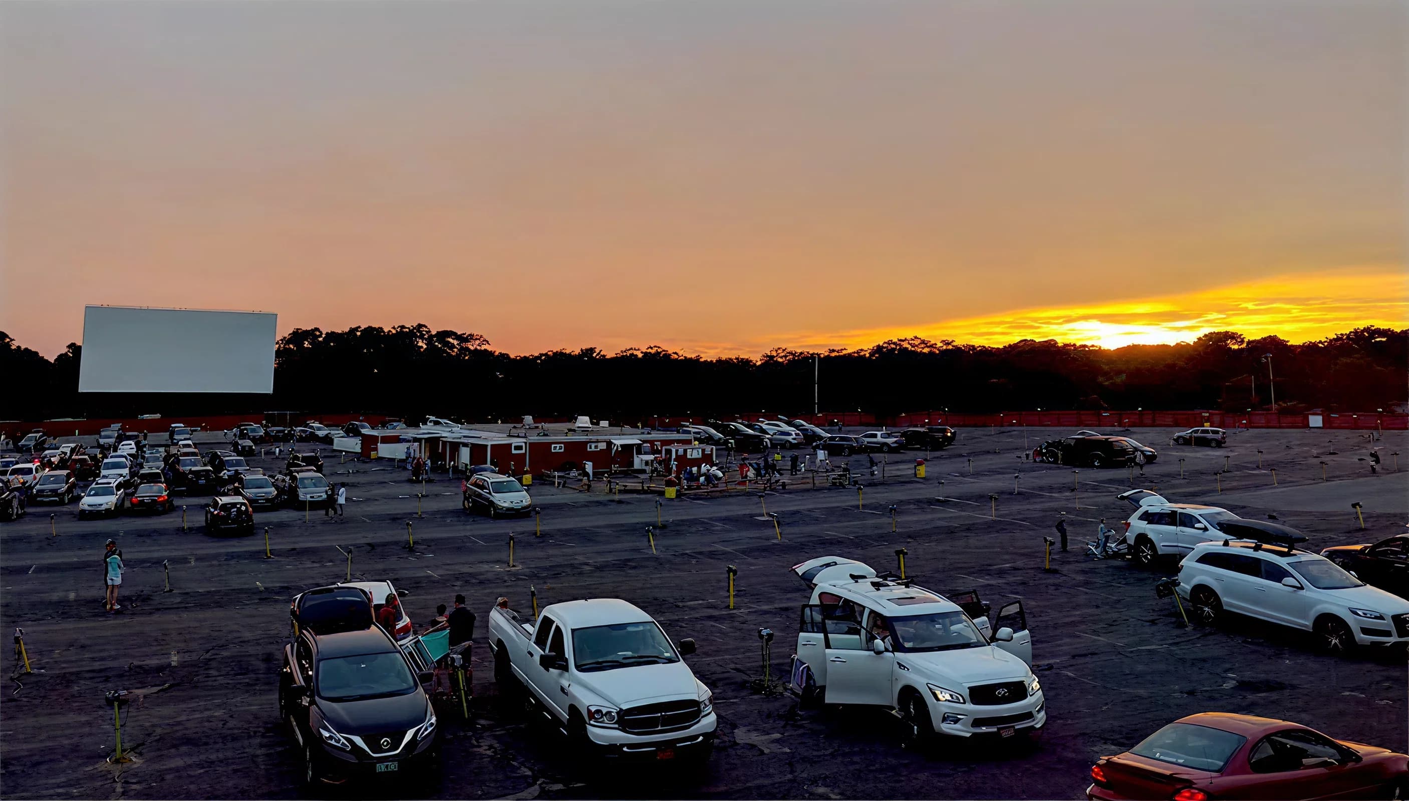 Cars lined up at the Wellfleet Drive-In at dusk with the large outdoor screen glowing